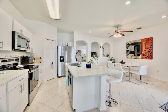 kitchen with a kitchen island with sink, stainless steel appliances, visible vents, white cabinets, and light countertops