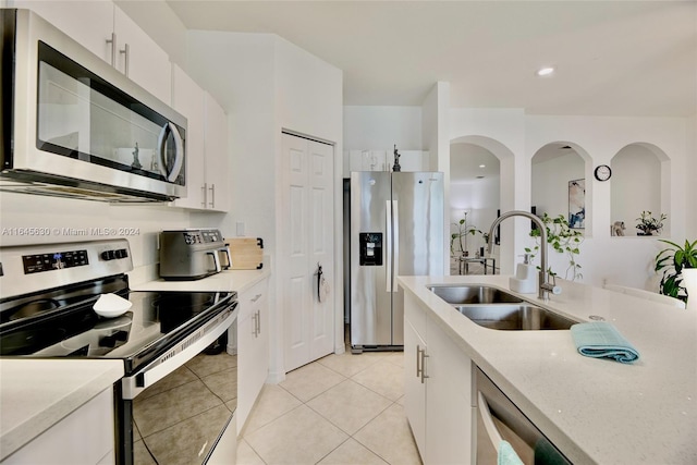 kitchen featuring stainless steel appliances, white cabinetry, a sink, and light tile patterned flooring