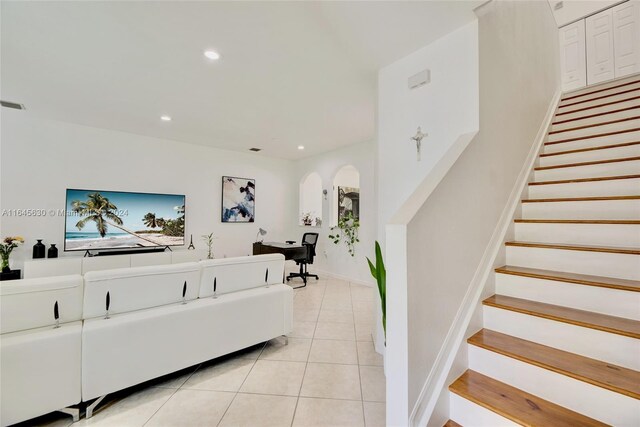 living room with light tile patterned flooring, stairway, arched walkways, and recessed lighting