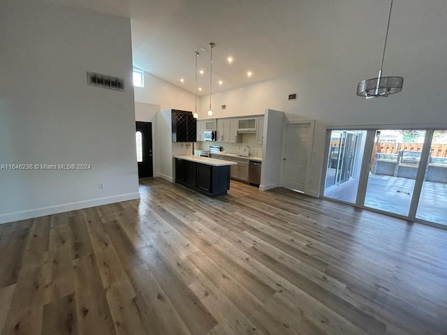 kitchen with pendant lighting, sink, high vaulted ceiling, appliances with stainless steel finishes, and hardwood / wood-style floors