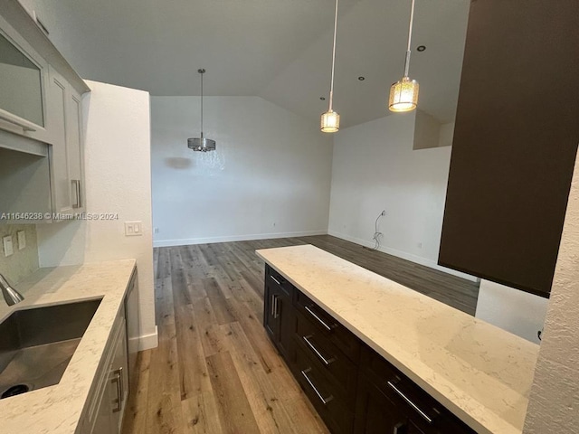 kitchen with light wood-type flooring, vaulted ceiling, sink, and pendant lighting