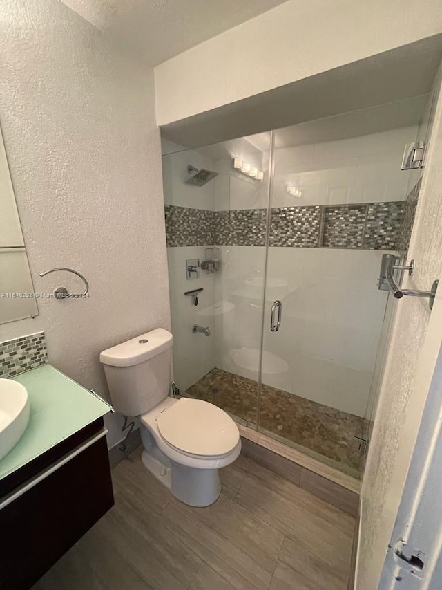 bathroom featuring hardwood / wood-style floors, a shower with door, vanity, and toilet