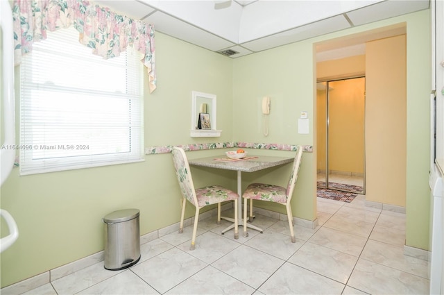 tiled dining space featuring a paneled ceiling