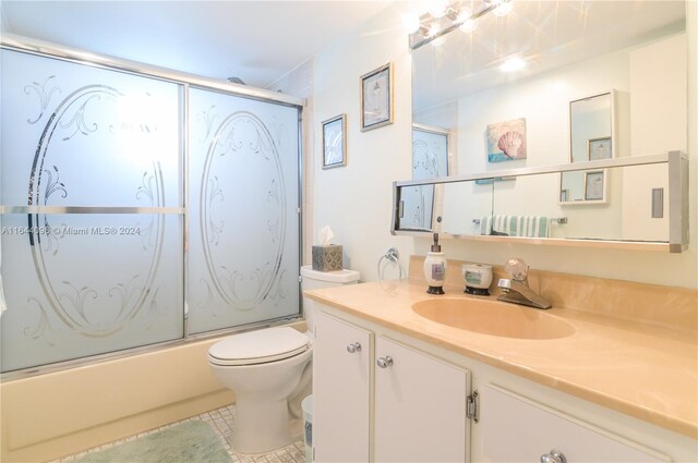 full bathroom with tile patterned floors, toilet, vanity, and enclosed tub / shower combo