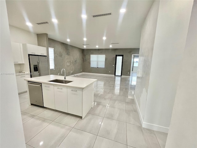 kitchen featuring white cabinetry, sink, stainless steel appliances, and an island with sink