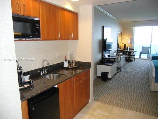 kitchen featuring dark stone countertops, light carpet, and black appliances