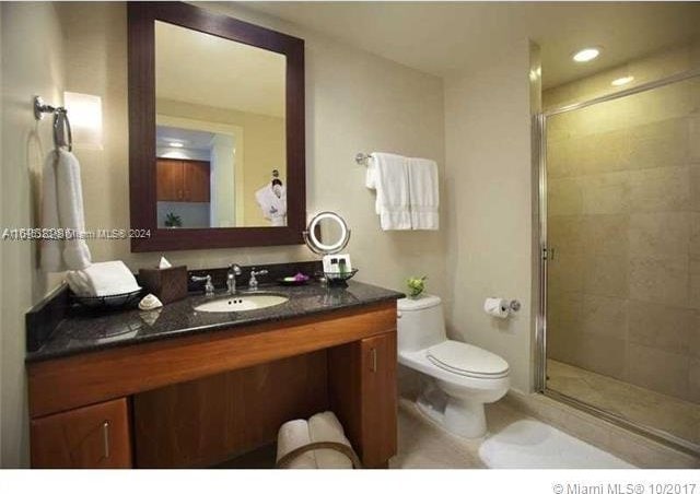 bathroom with a shower with door, toilet, and vanity