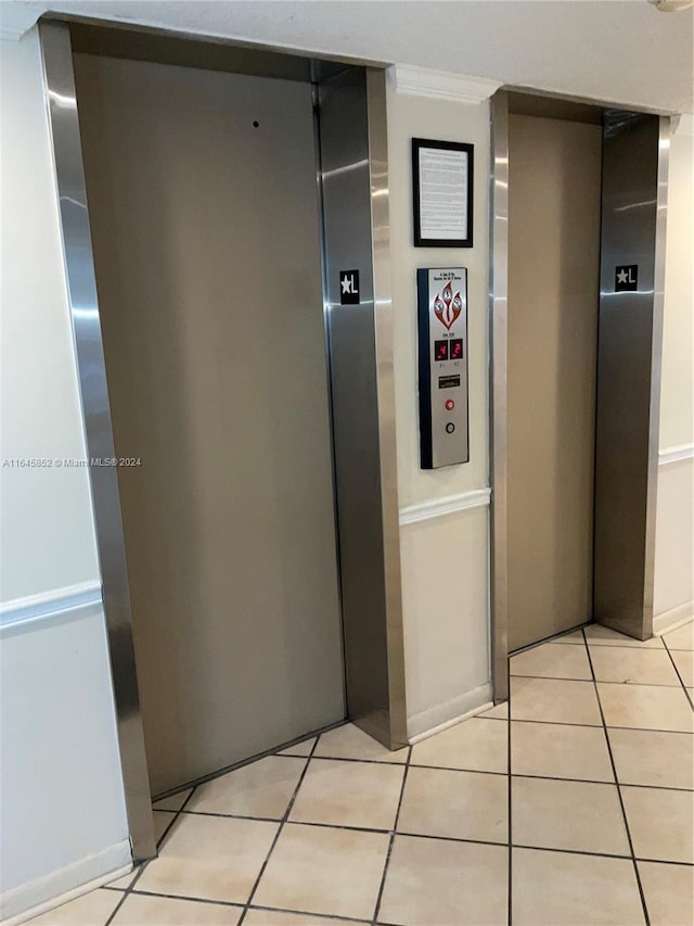 hall with ornamental molding, elevator, and light tile patterned floors