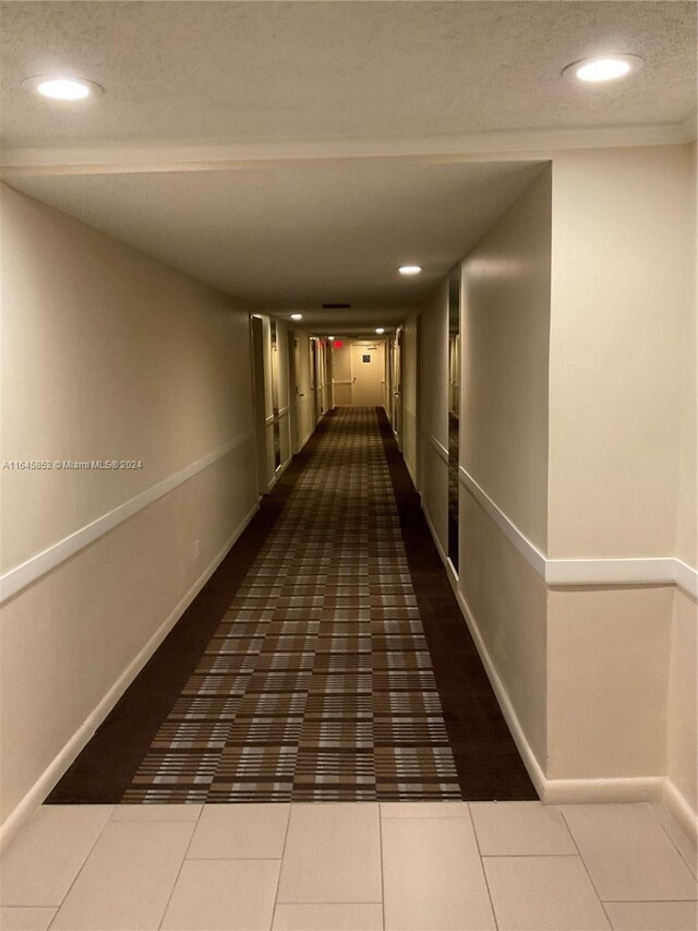 hallway featuring dark tile patterned flooring and a textured ceiling