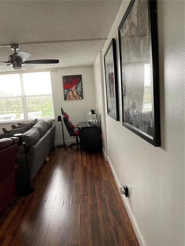 living room featuring dark hardwood / wood-style flooring, a textured ceiling, and ceiling fan