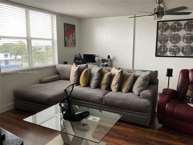 living room featuring ceiling fan, dark hardwood / wood-style floors, and a textured ceiling