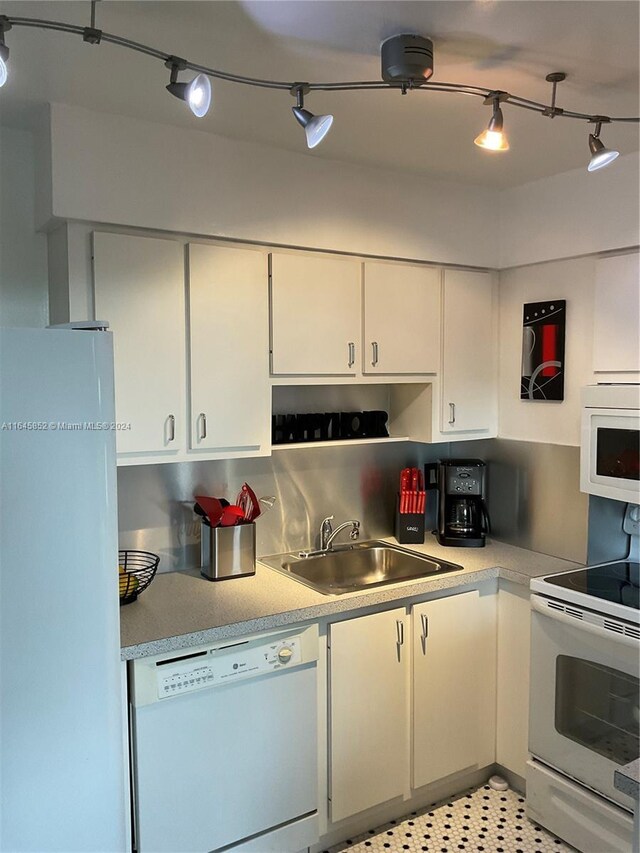 kitchen with light tile patterned floors, sink, white appliances, and white cabinets