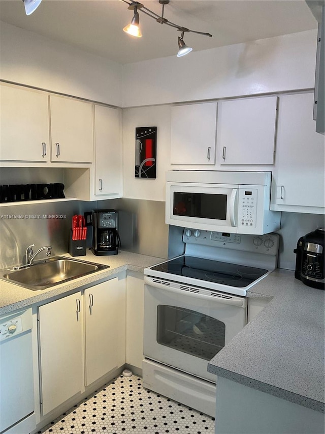 kitchen with sink, rail lighting, white appliances, light tile patterned floors, and white cabinets