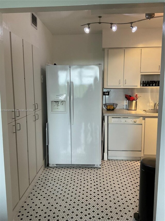 kitchen with sink, track lighting, light tile patterned flooring, and white appliances