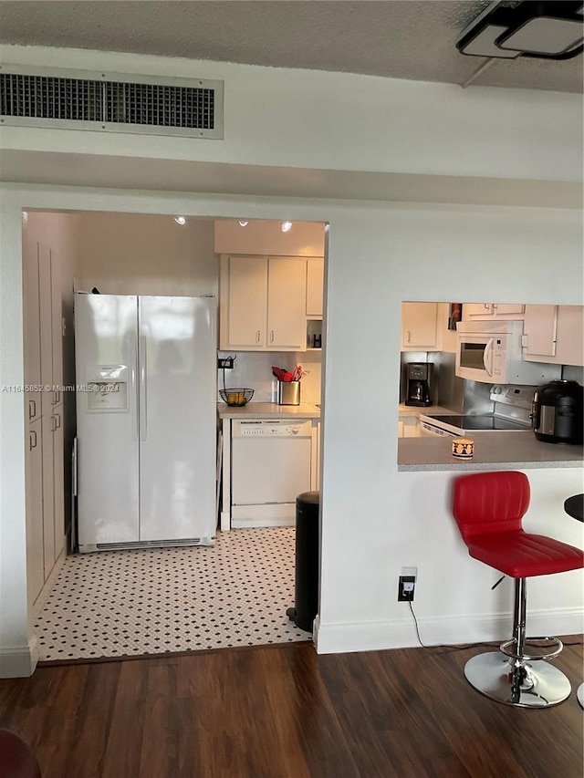 kitchen with white appliances, a breakfast bar, and dark hardwood / wood-style flooring