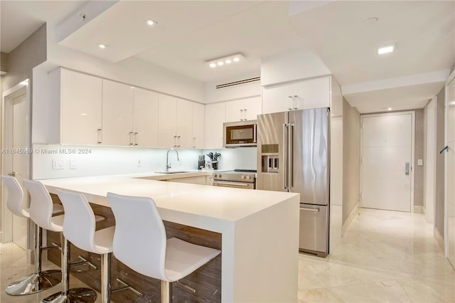 kitchen with appliances with stainless steel finishes, sink, light tile patterned floors, kitchen peninsula, and a breakfast bar