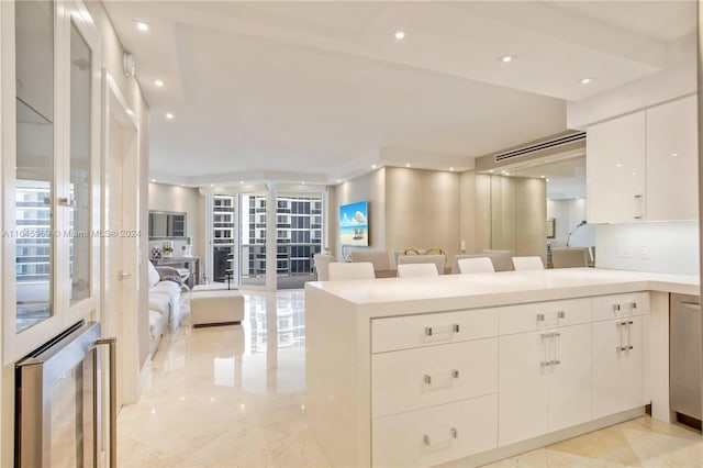 kitchen featuring light tile patterned floors, kitchen peninsula, a kitchen breakfast bar, and white cabinets