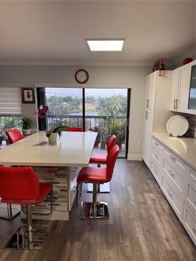 dining space featuring dark wood-type flooring, a healthy amount of sunlight, and ornamental molding