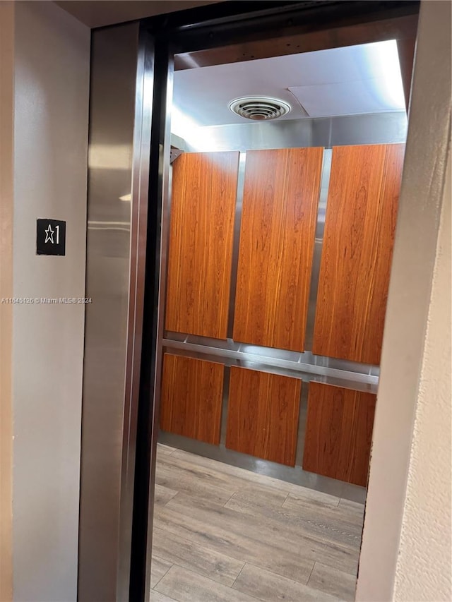 details featuring elevator, visible vents, and wood finished floors