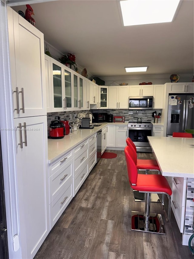 kitchen featuring stainless steel appliances, decorative backsplash, dark hardwood / wood-style floors, and white cabinetry