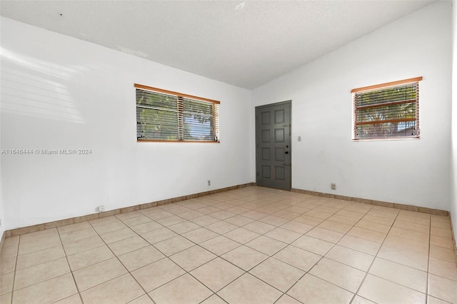 unfurnished room featuring lofted ceiling, a textured ceiling, and baseboards