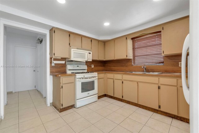 kitchen with backsplash, sink, white appliances, light brown cabinetry, and light tile patterned floors