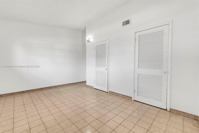 unfurnished bedroom featuring light tile patterned floors and two closets