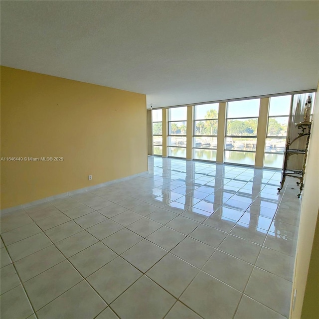 tiled empty room with a water view and expansive windows