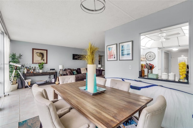 tiled dining room with a textured ceiling and ceiling fan