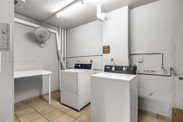 clothes washing area featuring washer and clothes dryer and light tile patterned flooring