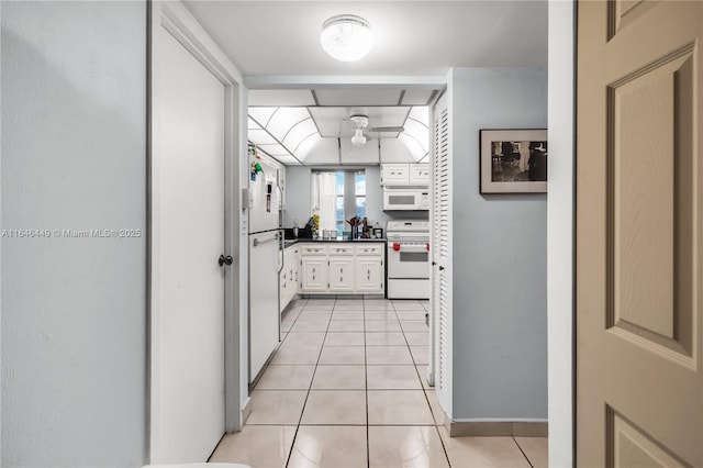 kitchen with white cabinets, white appliances, and light tile patterned flooring