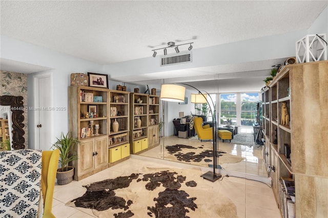 interior space with light tile patterned floors, a textured ceiling, and rail lighting