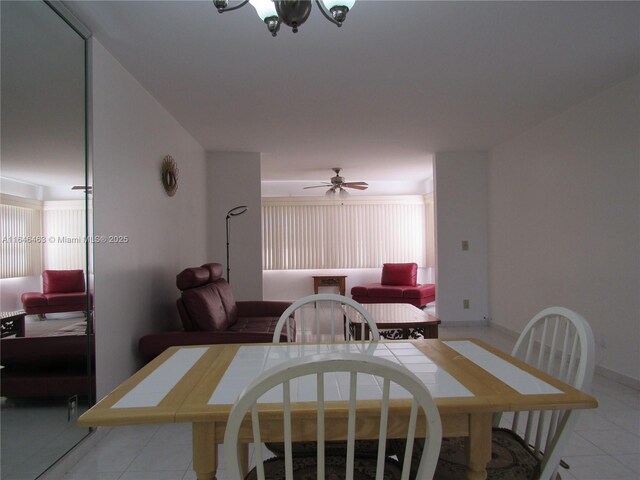 tiled dining space with ceiling fan with notable chandelier