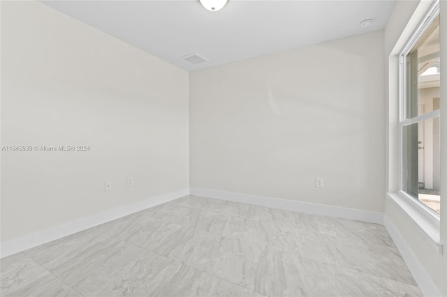 spare room with light tile patterned floors and a healthy amount of sunlight