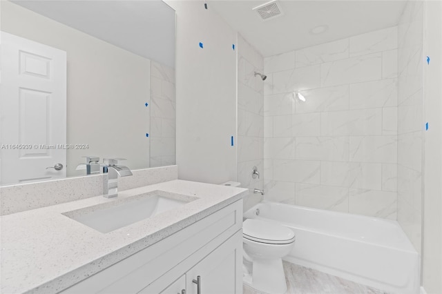 full bathroom featuring vanity, tiled shower / bath combo, and toilet