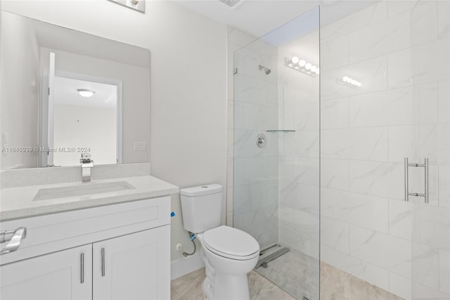 bathroom featuring toilet, tiled shower, vanity, and tile patterned floors