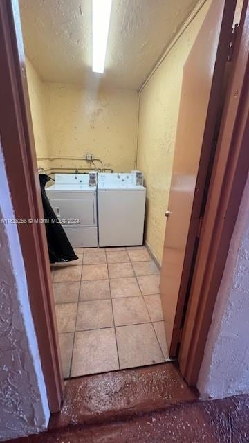 clothes washing area with washing machine and dryer and light tile patterned floors