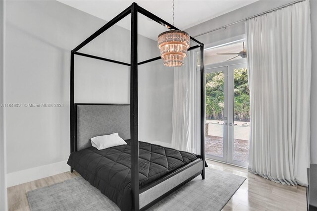 bedroom with light wood-type flooring, an inviting chandelier, french doors, and access to exterior