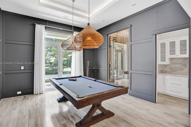 rec room with billiards, light hardwood / wood-style flooring, and a tray ceiling