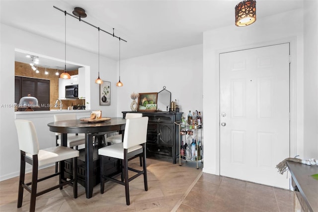 dining room with rail lighting, sink, and tile patterned floors