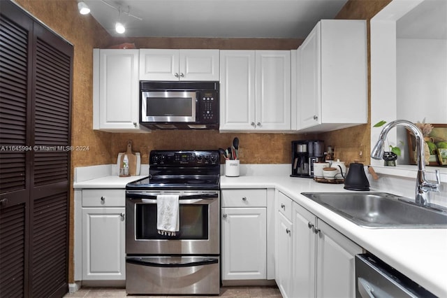 kitchen with appliances with stainless steel finishes, white cabinetry, and sink