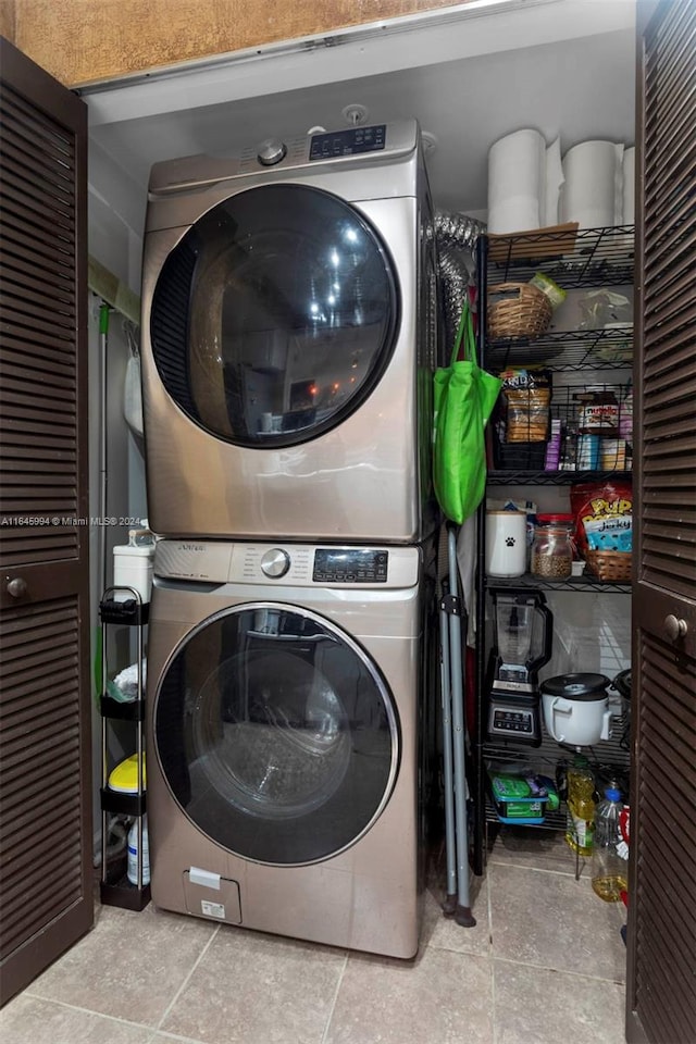 laundry area with stacked washer and clothes dryer and light tile patterned flooring