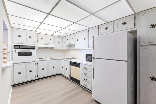 kitchen featuring light wood-type flooring, a paneled ceiling, white cabinets, sink, and white appliances