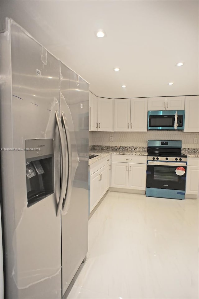 kitchen with light stone counters, stainless steel appliances, decorative backsplash, and white cabinetry