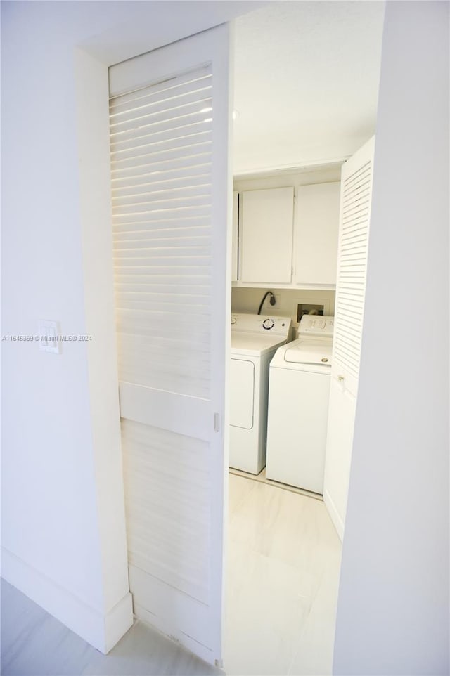 clothes washing area featuring cabinets and washer and dryer