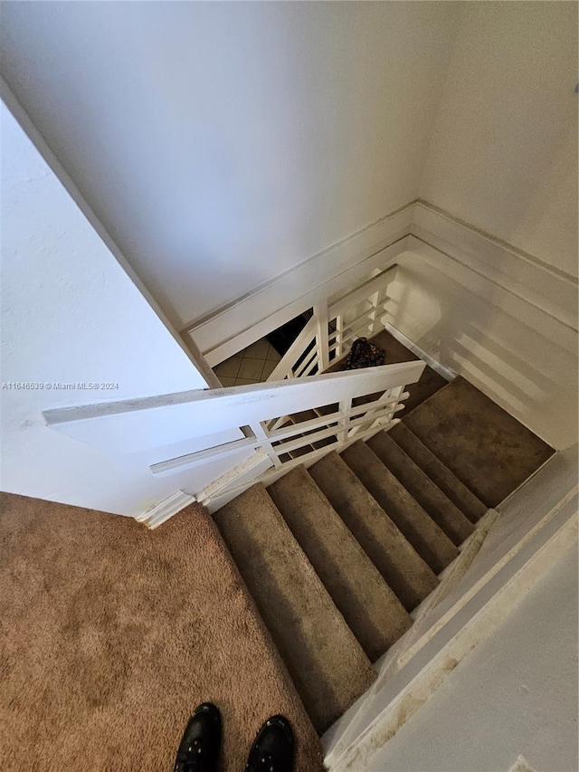 staircase with carpet floors and lofted ceiling