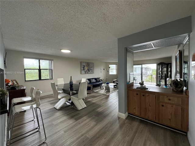 dining room featuring wood-type flooring, a textured ceiling, and a wealth of natural light