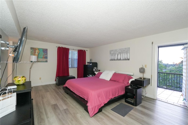 bedroom featuring light wood-type flooring, a textured ceiling, and access to exterior