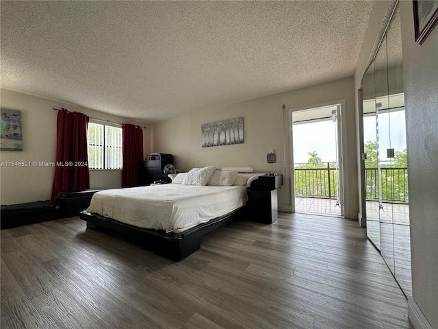 bedroom with a textured ceiling, hardwood / wood-style flooring, and access to outside