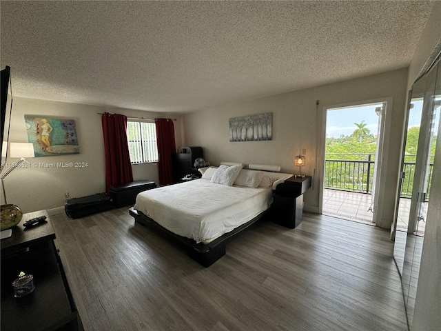 bedroom featuring access to exterior, a textured ceiling, and hardwood / wood-style floors